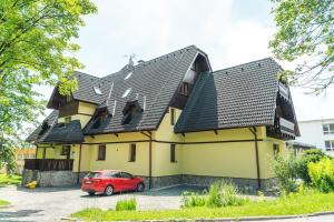 a red car parked in front of a yellow house at Lomnica Orange Apart in Tatranská Lomnica