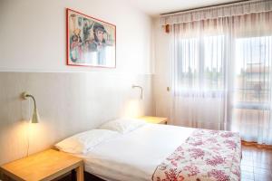 Un dormitorio con una cama blanca y una ventana. en Downtown apartment by the beach, en Eraclea Mare