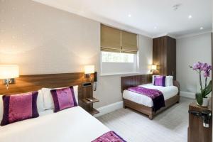 una camera con due letti e cuscini viola di London House Hotel a Londra