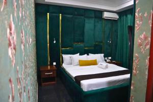 a bedroom with a bed with a green wall at ZiZi BY KDOVE HOTLES AND SUITES in Ikeja +2 photos