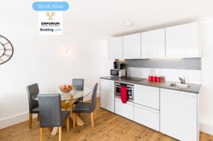 une cuisine avec des armoires blanches et une table avec des chaises dans l'établissement Brindley 2BDR Apartment By Emporium Property Management Short Lets & Serviced Accommodation Birmingham On The 15th Floor Offering Panoramic City Views With Free WiFi, à Birmingham 16 autres photos