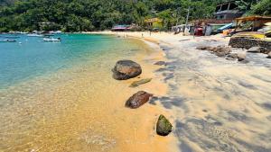 ein Strand mit Felsen im Sand und Wasser in der Unterkunft Pousada Zen in Angra dos Reis