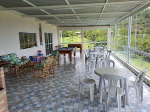 une pièce avec des tables, des chaises et des fenêtres dans l'établissement Sitio Recanto dos Passáros, à Caçapava