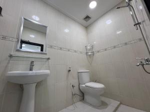 ein Badezimmer mit Waschbecken, Toilette und Spiegel in der Unterkunft Your Cozy Stay in Bahrain in Jurdāb + 10 Fotos