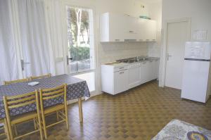een keuken met een tafel, een fornuis en een koelkast bij Apartment in pine forest near the beach in Eraclea Mare