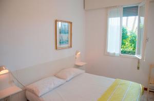 een witte slaapkamer met een bed en een raam bij Apartment in pine forest near the beach in Eraclea Mare