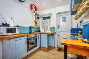 eine Küche mit blauen Schränken und einer Mikrowelle in der Unterkunft Finest Retreats - No 3 Sandside in Whitby