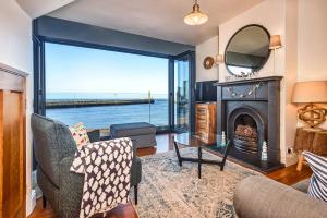 ein Wohnzimmer mit einem Kamin und Blick auf das Wasser in der Unterkunft Finest Retreats - No 3 Sandside in Whitby