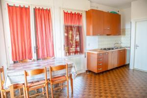 een keuken met een houten tafel en een aantal ramen bij Spacious first-floor flat near the beach in Eraclea Mare