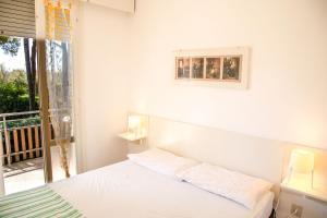 een witte slaapkamer met een bed en een balkon bij Spacious first-floor flat near the beach in Eraclea Mare