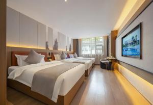 a hotel room with two beds and a flat screen tv at 张家界民宿 in Hanqiyu