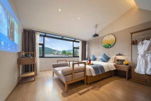 Un dormitorio con una cama y una silla y una ventana. en 柯凡酒店-近张家界森林公园,打车十分钟,线上英语服务,免费推荐游玩路线,预约门票, en Zhangjiajie