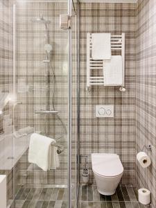 a bathroom with a shower and a toilet and towels at Mamaison Vibe Hotel Downtown Budapest in Budapest