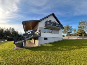 a house with a balcony on a grass field at Wypoczynek KOPANICA in Kopanica