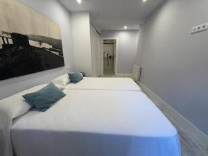 ein Schlafzimmer mit einem großen weißen Bett mit blauen Kissen in der Unterkunft Apartamento los Remos VUT-3207AS in Llanes