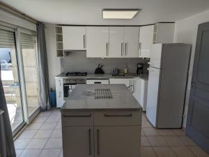 eine Küche mit weißen Schränken und einem weißen Kühlschrank in der Unterkunft Gîte proche du Futuroscope in Jaunay-Clan