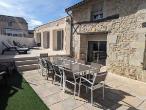 eine Terrasse mit Tisch und Stühlen vor einem Gebäude in der Unterkunft Gîte proche du Futuroscope in Jaunay-Clan
