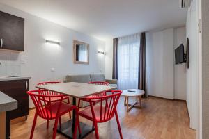 uma sala de estar com uma mesa e cadeiras vermelhas em Residhotel Mulhouse Centre em Mulhouse