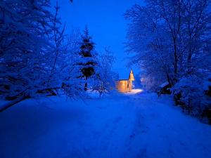 a snow covered road with a church in the background at Chatô Liptov in Liptovský Mikuláš