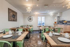 uma sala de jantar com mesas de madeira e cadeiras verdes em Residhotel Mulhouse Centre em Mulhouse