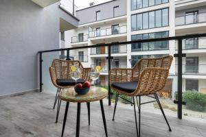 a balcony with three chairs and a table with a bowl of fruit at Unique Studio with Parking Space and Swimming Pool by Noclegi Renters in Pobierowo