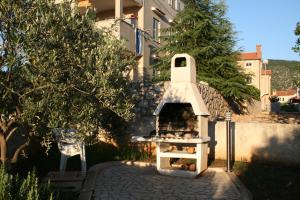 a outdoor pizza oven in a yard next to a tree at Apartments Duomo in Cres