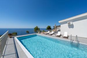 ein Swimmingpool mit Stühlen und das Meer im Hintergrund in der Unterkunft Areti-Elena Oxomeria in Katsimátika