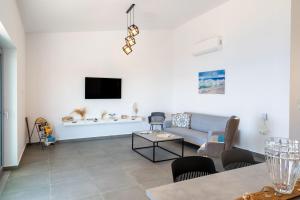 ein Wohnzimmer mit einer Couch und einem Fernseher an der Wand in der Unterkunft Areti-Elena Oxomeria in Katsimátika