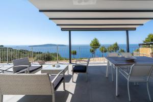 eine Terrasse mit Tisch und Stühlen und dem Meer in der Unterkunft Areti-Elena Oxomeria in Katsimátika