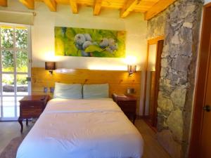 Un dormitorio con una cama y una pared de piedra. en Hotel Boutique Frutos del bosque de Zacatlan, en Jicolapa