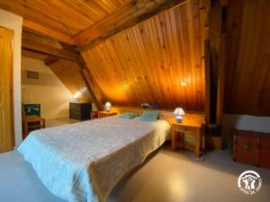 a bedroom with a large bed and wooden walls at le Chouette in Saint-Cyprien-sur-Dourdou