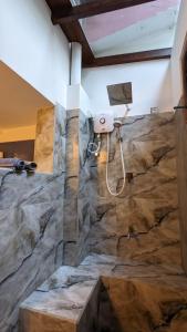 um banheiro com parede de pedra e box de chuveiro em Abraham Beach House em Tangalle