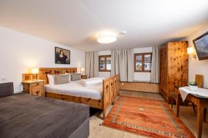 Un dormitorio con una cama, una mesa y un sofá. en Landhaus Schösser-Brandler, en Mayrhofen