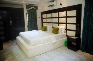 um quarto com uma grande cama branca com travesseiros verdes em Luxurious Duplex in Oredo, Benin City - Perfect for Families and Groups em Ekae