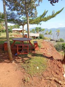 a picnic table sitting on a hill next to the water at Lakeside Beach Hotel in Madwa