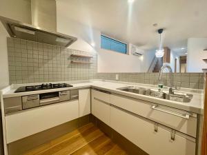 a white kitchen with a sink and a stove at Villa Monica Premium in Nagoya