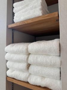 une pile de serviettes blanches sur une étagère dans l'établissement Villa Monica Premium, à Nagoya 29 autres photos