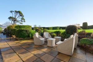 a patio with white chairs and trees and bushes at Manor House Apartment - Indoor Heated Pool, Parking in Torquay