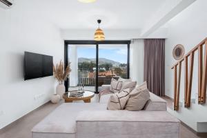 a living room with a couch and a tv at Pamboo Ampelos House by Nomads in Statos and Ayios Photios