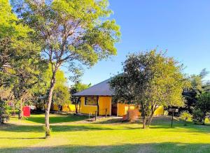 a yellow house with trees in front of it at Cabañas La Soñada in Chajarí