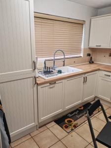 Una cocina con gabinetes blancos y un fregadero y una ventana. en Festohomes1 at rushden, en Rushden