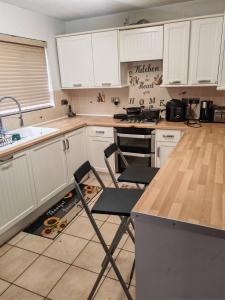 Una cocina con gabinetes blancos y una mesa y sillas. en Festohomes1 at rushden, en Rushden