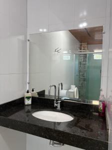 Un mostrador de baño con un lavabo y un espejo. en Quarto privado próximo ao centro 13, en Manaus