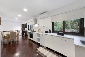 a kitchen with white cabinets and a dining room at Casa São Domingos in Travanca