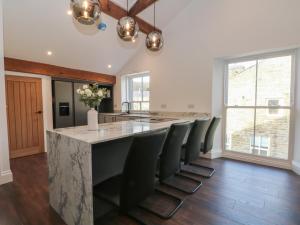 a kitchen with a large island with black chairs at The Penthouse at 86 in Rossendale
