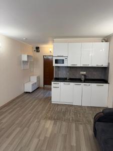 een keuken met witte kasten en een woonkamer bij Prestige Tower Batumi in Itʼkhvisi