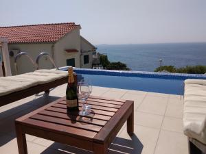a bottle of wine on a wooden table next to a pool at Apartments Jana in Primošten