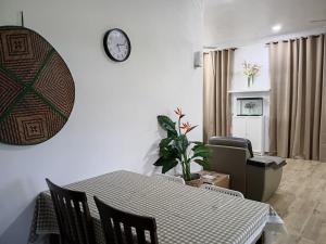 ein Esszimmer mit einem Tisch und einer Uhr an der Wand in der Unterkunft ANTA Homestay with private pool in Kota Kinabalu