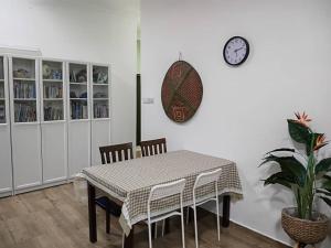 ein Esszimmer mit einem Tisch und einer Uhr an der Wand in der Unterkunft ANTA Homestay with private pool in Kota Kinabalu
