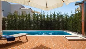 a swimming pool with a bench and an umbrella at Luxury villa Adele with pool in Porec in Vabriga